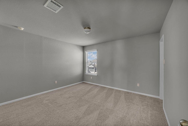 carpeted spare room featuring visible vents, a textured ceiling, and baseboards