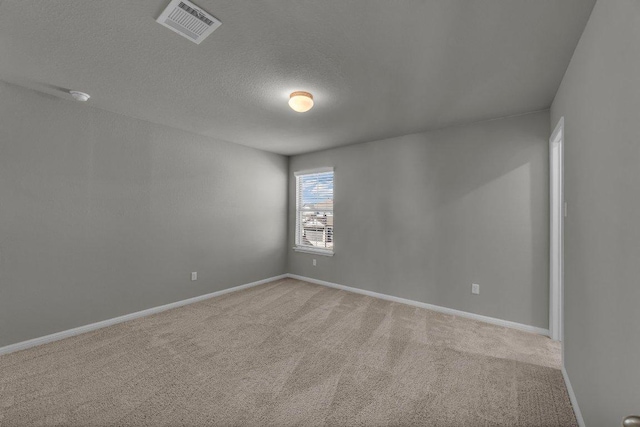 spare room featuring baseboards, visible vents, a textured ceiling, and light colored carpet