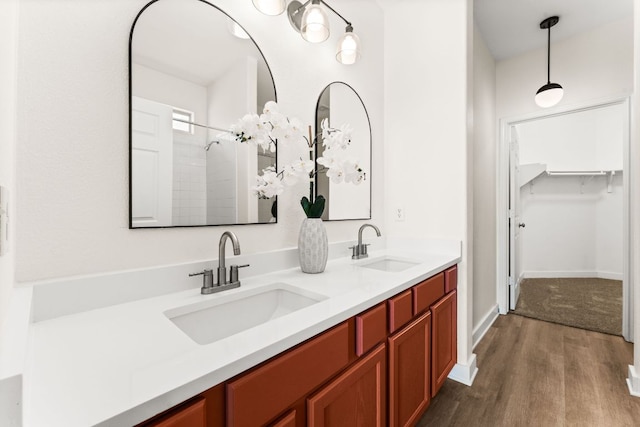 bathroom featuring double vanity, baseboards, a sink, and wood finished floors