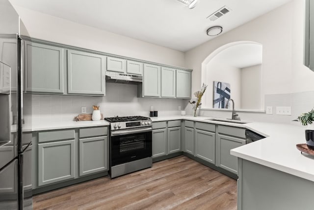 kitchen with visible vents, gas range, gray cabinets, under cabinet range hood, and a sink