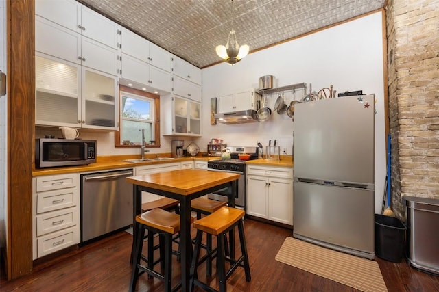 2300 Willow St, Austin, TX 78702 - kitchen with stainless steel appliances, under cabinet range hood, butcher block counters, dark wood finished floors, and an ornate ceiling