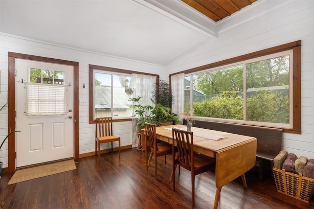 dining space featuring plenty of natural light, dark wood-type flooring, wood walls, and vaulted ceiling with beams