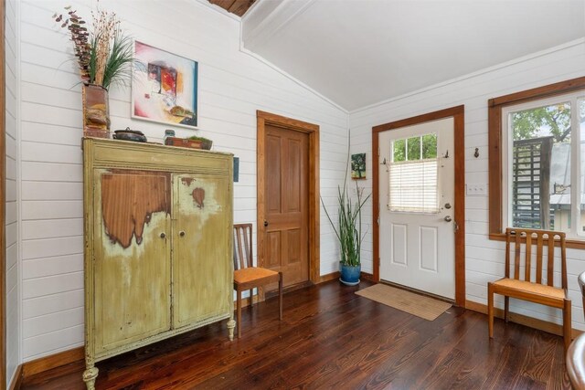 entryway with wooden walls, baseboards, dark wood-type flooring, and lofted ceiling