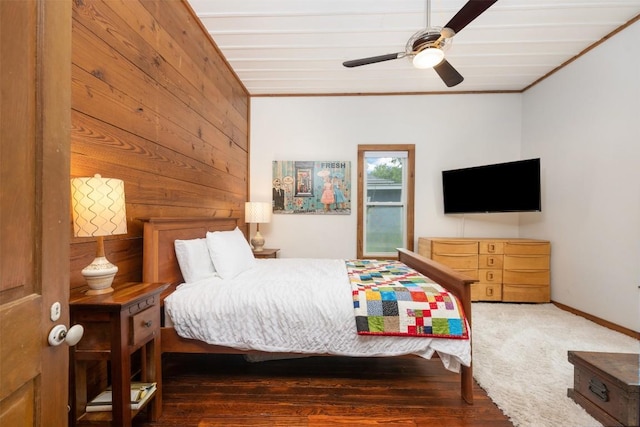 bedroom featuring wooden walls, baseboards, ornamental molding, wood finished floors, and a ceiling fan