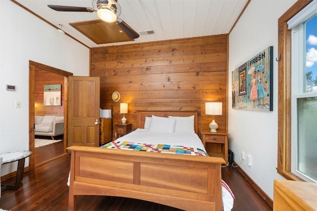 bedroom with visible vents, multiple windows, wooden walls, and dark wood-style flooring