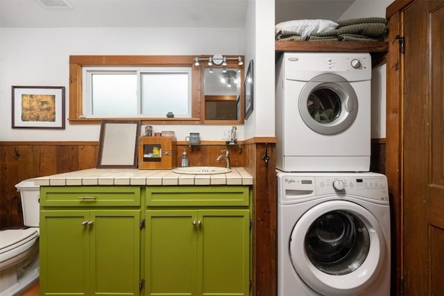 2300 Willow St, Austin, TX 78702 - laundry area featuring stacked washing machine and dryer and wainscoting