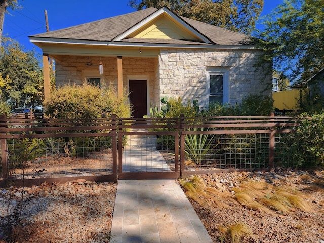 2300 Willow St, Austin, TX 78702 - view of front of house featuring stone siding, a shingled roof, and a gate