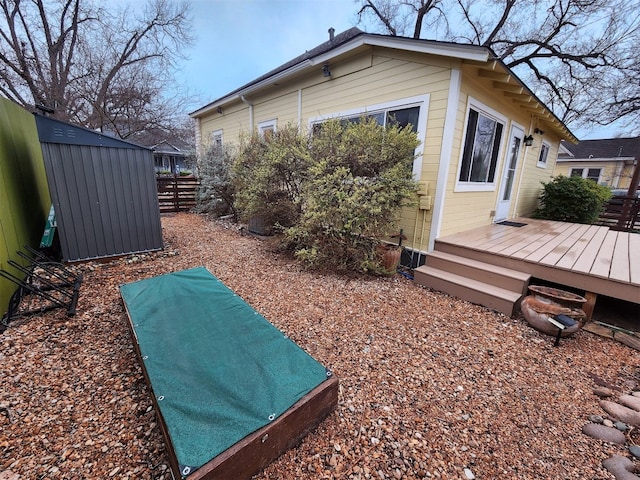 view of side of home with an outbuilding, a wooden deck, and fence