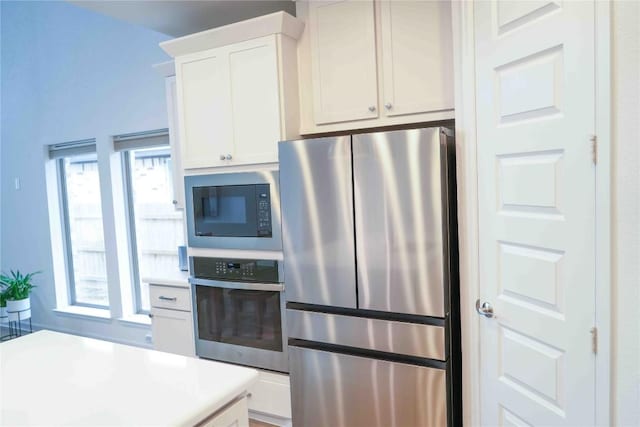 kitchen featuring appliances with stainless steel finishes, light countertops, and white cabinetry