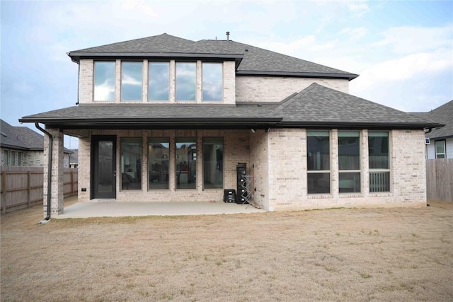 rear view of property featuring a patio area, a shingled roof, a fenced backyard, and brick siding