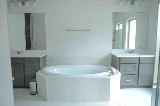 bathroom with tile patterned floors, two vanities, a sink, and a bath