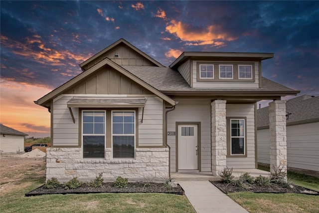 craftsman inspired home with stone siding, a shingled roof, and board and batten siding