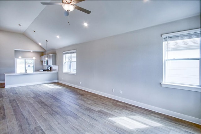 unfurnished living room featuring dark wood-style floors, vaulted ceiling, baseboards, and a ceiling fan