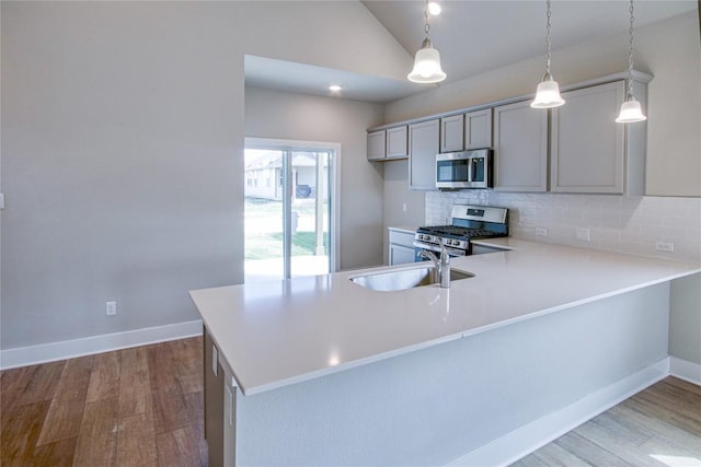 kitchen featuring stainless steel appliances, a sink, a peninsula, and tasteful backsplash