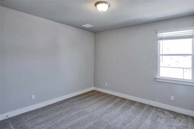 spare room with carpet, visible vents, and baseboards