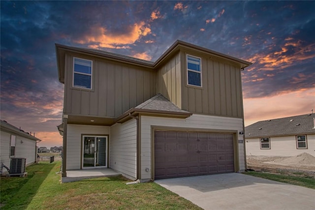 view of front of home with a yard, an attached garage, board and batten siding, cooling unit, and driveway