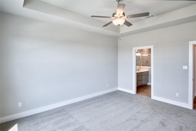 205 Pinnacle Ln, Kyle, TX 78640 - unfurnished bedroom with carpet, baseboards, a tray ceiling, ensuite bathroom, and ceiling fan
