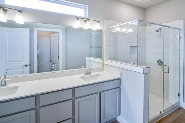 full bathroom featuring double vanity, a stall shower, and a sink