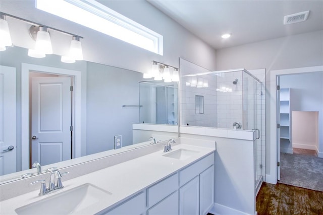 full bathroom featuring visible vents, a sink, a shower stall, and double vanity