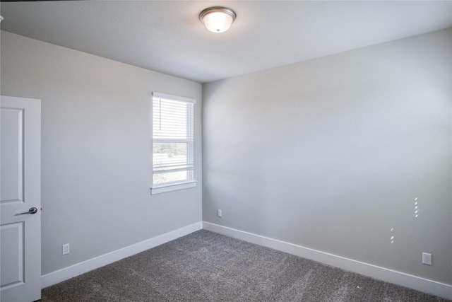 empty room with dark colored carpet and baseboards