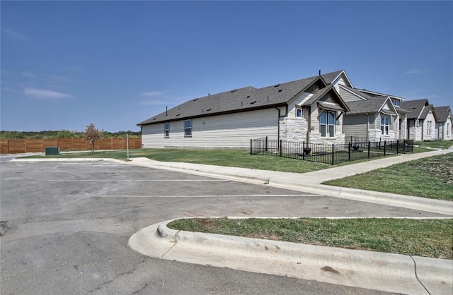 exterior space featuring fence private yard, uncovered parking, stone siding, and a yard