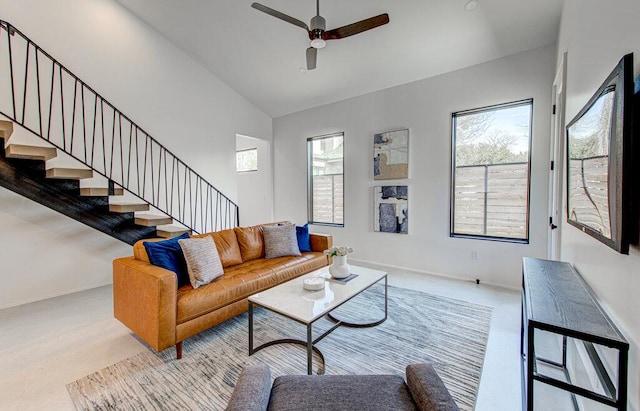 living room with a ceiling fan, high vaulted ceiling, baseboards, and stairs