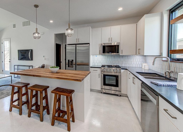 kitchen featuring tasteful backsplash, visible vents, appliances with stainless steel finishes, a kitchen breakfast bar, and a sink