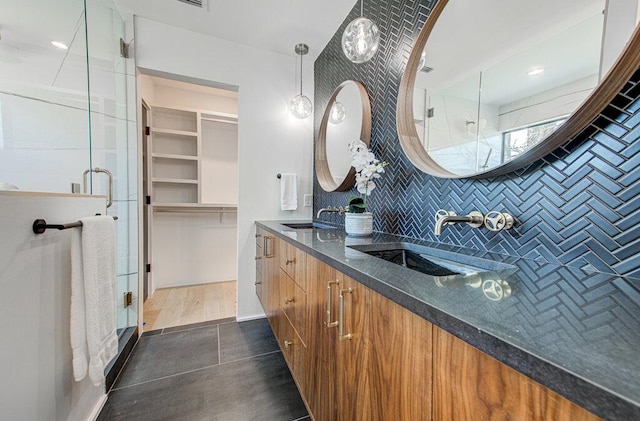 full bathroom with double vanity, a stall shower, a spacious closet, and a sink