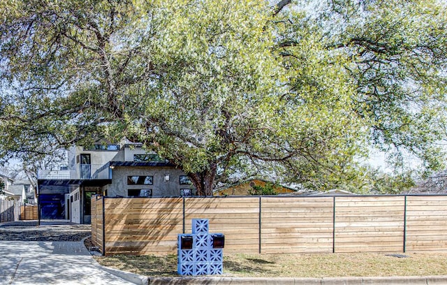 view of front of property with driveway, fence private yard, and a balcony