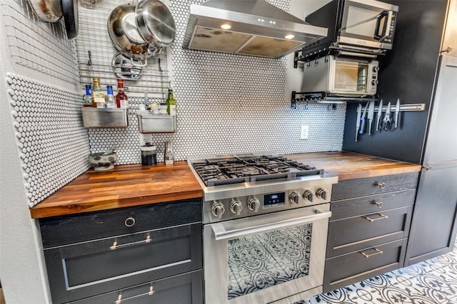 kitchen featuring decorative backsplash, high end range, wall chimney range hood, and wooden counters