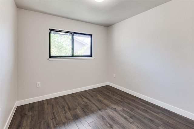 empty room with dark wood-type flooring and baseboards