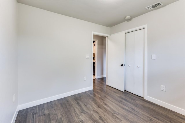 unfurnished bedroom featuring visible vents, baseboards, a closet, and dark wood-style flooring