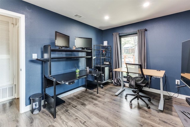 office area with a textured wall, visible vents, baseboards, and wood finished floors