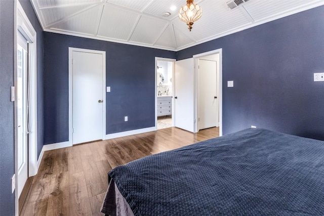 bedroom featuring visible vents, connected bathroom, baseboards, and wood finished floors