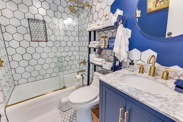 full bathroom featuring combined bath / shower with glass door, toilet, vanity, and a textured wall