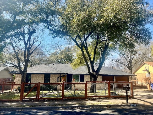 single story home with a gate, stone siding, a fenced front yard, and a shingled roof