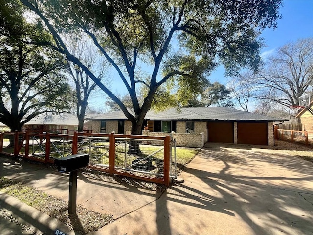 ranch-style house with concrete driveway, an attached garage, fence, and brick siding