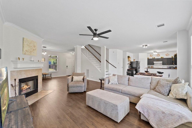 living room featuring a fireplace, visible vents, stairway, dark wood-type flooring, and baseboards