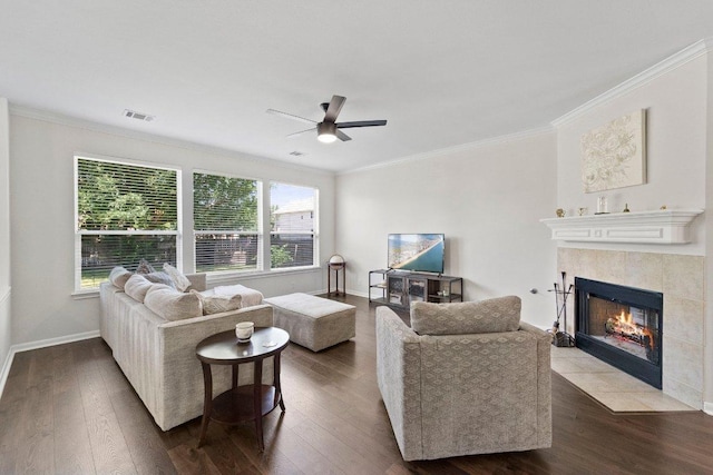 living room featuring visible vents, a tiled fireplace, and wood finished floors