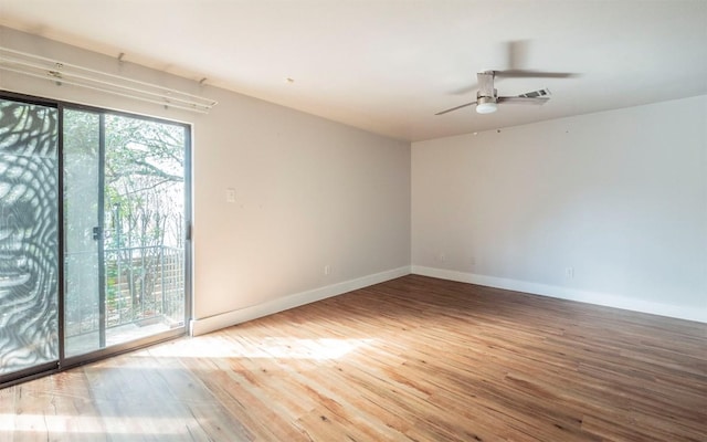 unfurnished room featuring ceiling fan, wood finished floors, a wealth of natural light, and baseboards