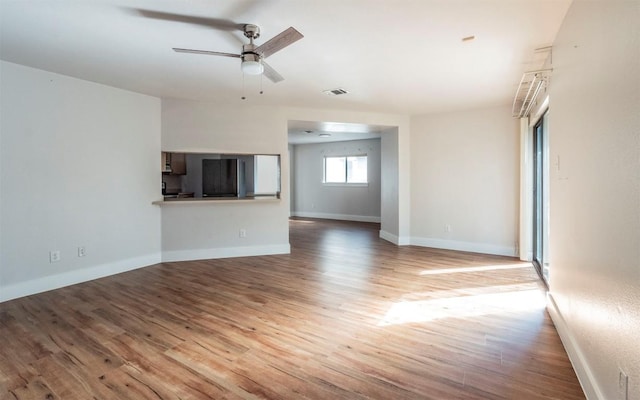 unfurnished living room featuring visible vents, ceiling fan, baseboards, and wood finished floors