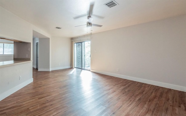 unfurnished room with ceiling fan, wood finished floors, visible vents, and baseboards