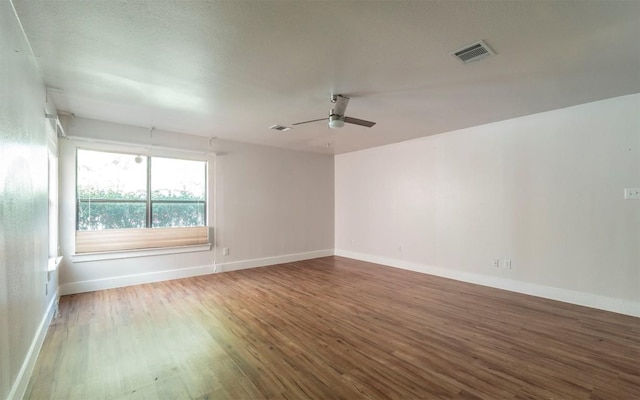 spare room featuring visible vents, ceiling fan, baseboards, and wood finished floors