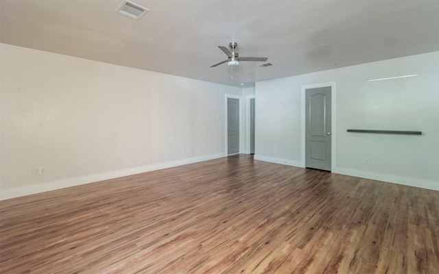 spare room with a ceiling fan, visible vents, baseboards, and wood finished floors