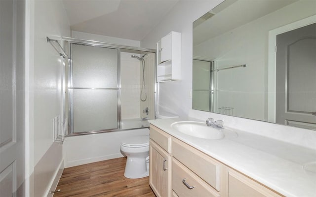 full bath featuring toilet, wood finished floors, vanity, and enclosed tub / shower combo