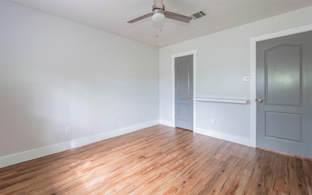 spare room featuring ceiling fan, wood finished floors, visible vents, and baseboards