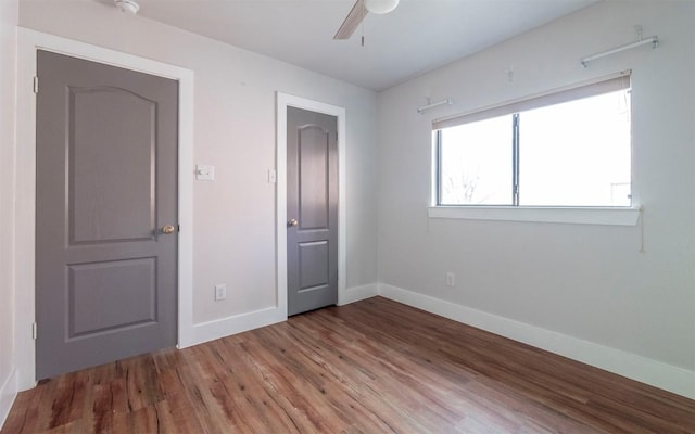 unfurnished bedroom with ceiling fan, baseboards, and wood finished floors