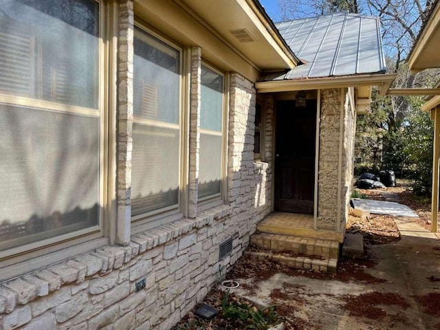 view of exterior entry with crawl space, metal roof, and a standing seam roof