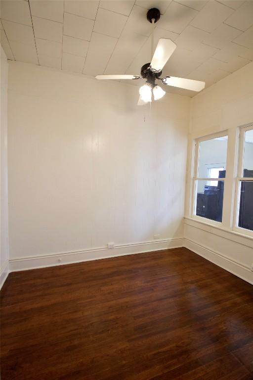 empty room with ceiling fan, baseboards, and dark wood finished floors