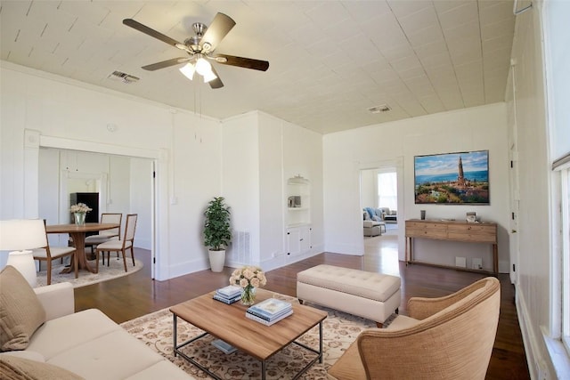 living area with a ceiling fan, visible vents, and wood finished floors